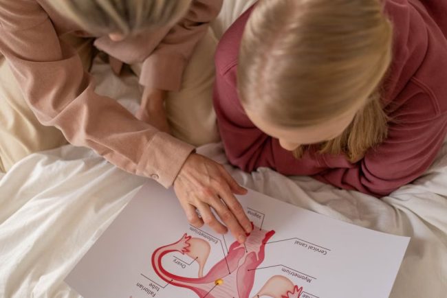 Mother and daughter studying reproductive system illustration for sex education at home.